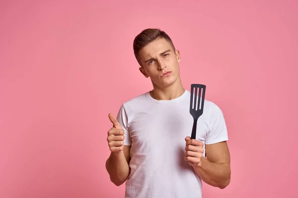 Homem com ferramentas de cozinha em espátula de fundo rosa para cozinhar modelo corte vista — Fotografia de Stock