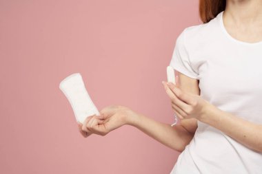 Elinde ped ve tampon olan bir kız. Pembe arka plan adet dönemi. Hijyen konusunda kritik günler.