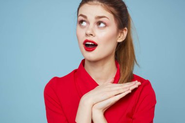 Mavi arka planda parlak elbiseli çekici bir kadın elleri ve kırmızı dudaklarıyla jestler yapıyordu.