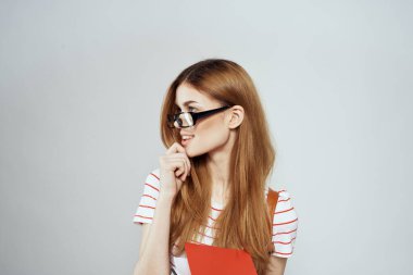 Sırtında not defteri ve sırt çantası olan bayan öğrenci bilim gözlüklerini kırpmış.