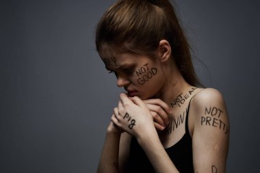 Vücudunda yazılar olan duygusal kadın hüsrandan dolayı gri arka planda.