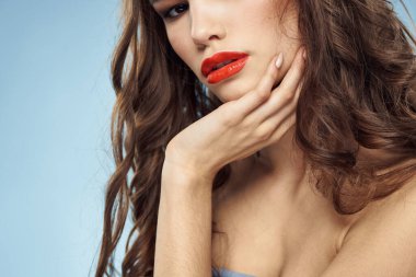 Güzel bir kadın. Çıplak omuzlar. Saç bakım, parlak makyaj, mavi arka plan.