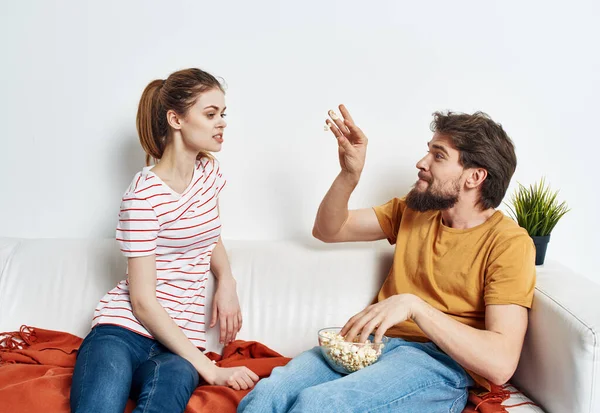 Erkek ve kadın kanepede arkadaşlarıyla sohbet ediyor patlamış mısır yiyor. — Stok fotoğraf