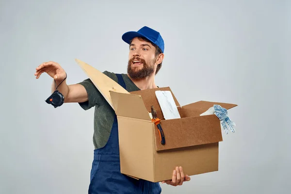 Homem no trabalho uniforme com caixa nas mãos ferramentas estilo de vida fundo leve — Fotografia de Stock