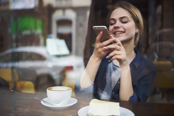 Frau mit Handy in der Hand plaudert Frühstück in einem Café — Stockfoto