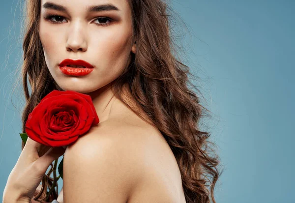 Sexy žena s červenou růží a modrým pozadím s brunetkou kudrlinky — Stock fotografie