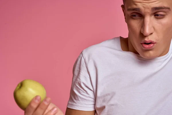 Hombre con frutas en las manos sobre un fondo rosa alimentos saludables vitaminas rosa fondo blanco camiseta modelo — Foto de Stock