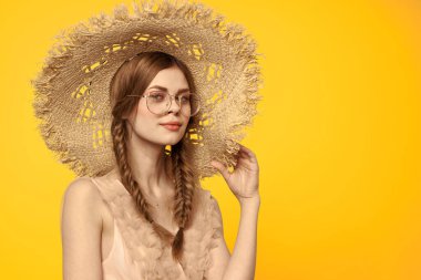 Sarı arka planda saman şapkalı portre kadın. Yazlık elbise mankeni romantizmi.