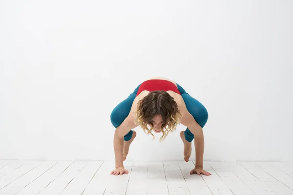 Mujer haciendo yoga de cuerpo entero en interiores polainas azules camiseta roja —  Fotos de Stock