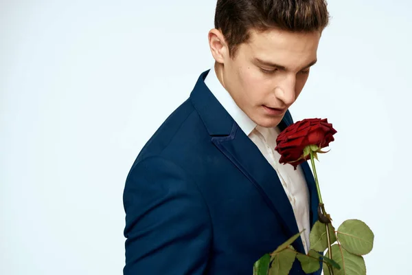 Un homme en costume avec une rose dans ses mains un cadeau date fond clair — Photo