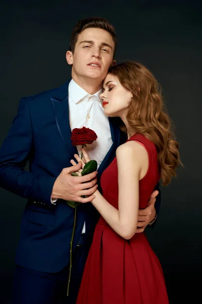 年轻夫妇拥抱迷人的红玫瑰关系黑色背景 — 图库照片
