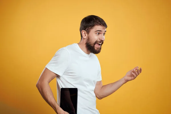 Чоловік з планшетом на жовтому тлі в білій футболці нові технології бізнесмен сенсорний екран тачпад — стокове фото