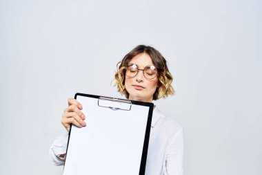 Elinde beyaz dökümanların olduğu bir klasör olan iş kadını arka planda ve saç stili gözlüklü model