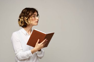 Elinde not defteri olan kadın iş hayatında bej arka plan gözlüklü saç stili.