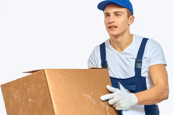 Man worker with box in hands delivery loading service work light background — Stock Photo, Image