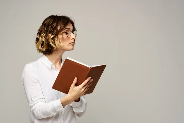 Γυναίκα με σημειωματάριο στα χέρια των επιχειρήσεων εργασία μπεζ γυαλιά φόντο χτένισμα — Φωτογραφία Αρχείου