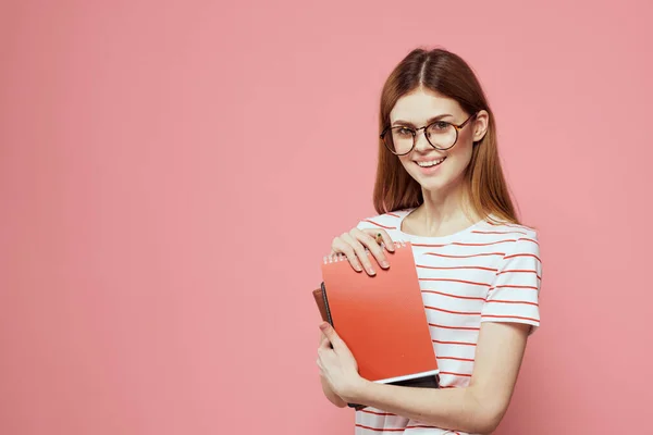 Női tanuló jegyzetfüzet rózsaszín háttér gesztikulál kezével szemüveg az arcán csíkos póló modell — Stock Fotó