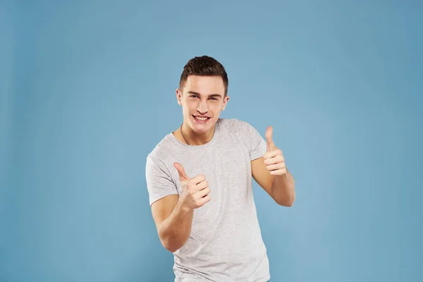 Cheerful man in a white t-shirt gesturing with his hands emotions blue background — Stock Photo, Image