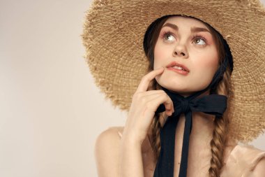 Siyah kurdeleli, saman şapkalı ve bej arka planda kırpılmış manzaralı şirin bir kız.