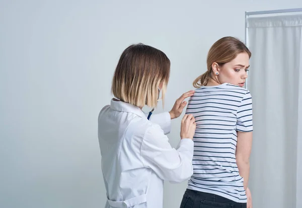 Жінка-лікар в медичній сукні зі стетоскопом слухає серце пацієнтів — стокове фото