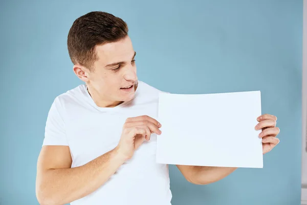 Homme tenant une feuille de papier dans ses mains blanc t-shirt recadré vue fond bleu — Photo