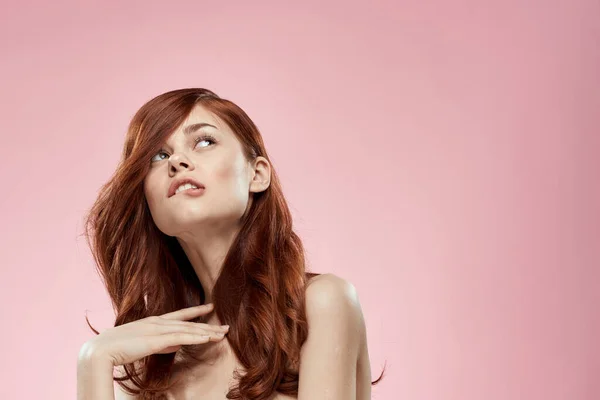 Красивая женщина с длинными красивыми волосами уход за прической гламур голые плечи розовый фон — стоковое фото