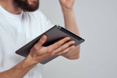 Açık arkaplanda dokunmatik ekranlı tablet erkek elleri beyaz tişört kırpılmış görünüm