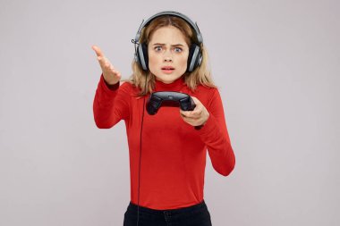 Kulaklıklı bir kadın elinde Joystick ile oyun oynuyor eğlence amaçlı eğlence amaçlı yaşam tarzı kırmızı gömlek gri arka plan