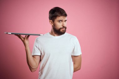 Pembe arka planda dizüstü bilgisayarı olan duygusal adam kırpılmış görünüm kopyalama alanı