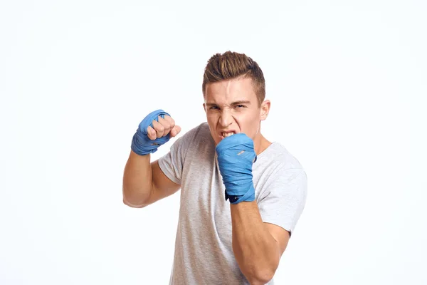 Boxeador masculino deportivo con guantes azules practicando golpes sobre un fondo claro recortado vista — Foto de Stock