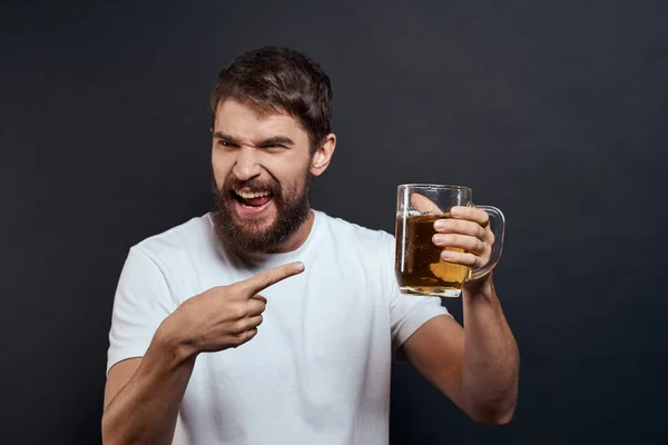 Чоловік з чашкою пива в руках емоції веселий спосіб життя біла футболка темно-ізольований фон — стокове фото