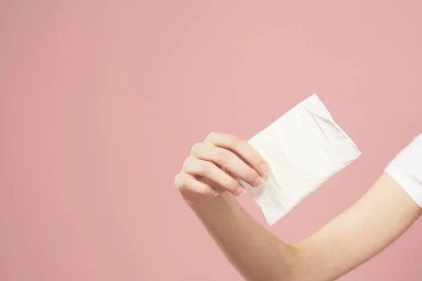 在粉红的背景上，用女性的手把它放在包装里，保持干净的外观 — 图库照片