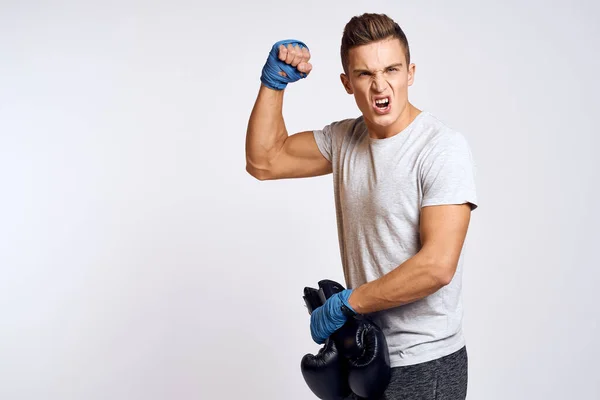 Hombre fuerte con guantes de boxeo y en una camiseta blanca sobre un fondo aislado recortado vista del modelo — Foto de Stock