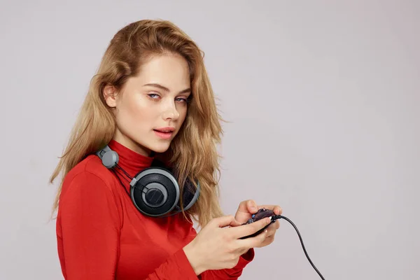 拿着耳机的女人手拿着游戏机玩乐休闲红色夹克生活方式浅薄的背景 — 图库照片