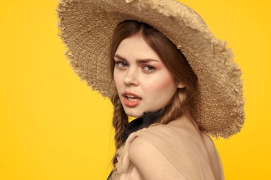 Sarı arka planda saman şapkalı portre kadın. Yazlık elbise mankeni romantizmi.