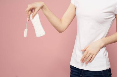 Elinde ped ve tampon olan bir kız. Pembe arka plan adet dönemi. Hijyen konusunda kritik günler.