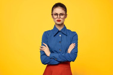 Mavi gömlekli ve kırmızı gözlüklü kadın kendine güvenen portre sarı arka plan kırpılmış görünüm