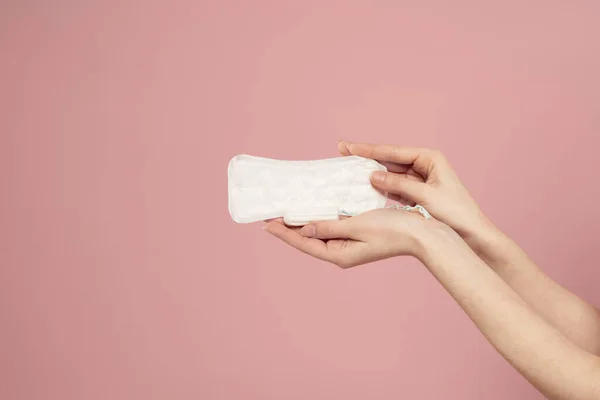 Coussinet protecteur et tampon dans les mains féminines sur un fond rose menstruations jours critiques — Photo