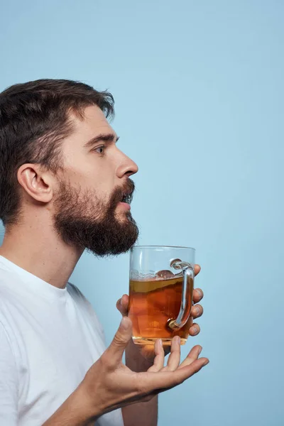 Homem barbudo caneca de cerveja álcool branco t-shirt vista lateral azul fundo — Fotografia de Stock