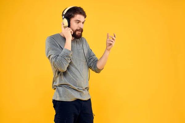 Man in hoofdtelefoon luistert naar muziek technologie levensstijl leuke mensen gele achtergrond — Stockfoto