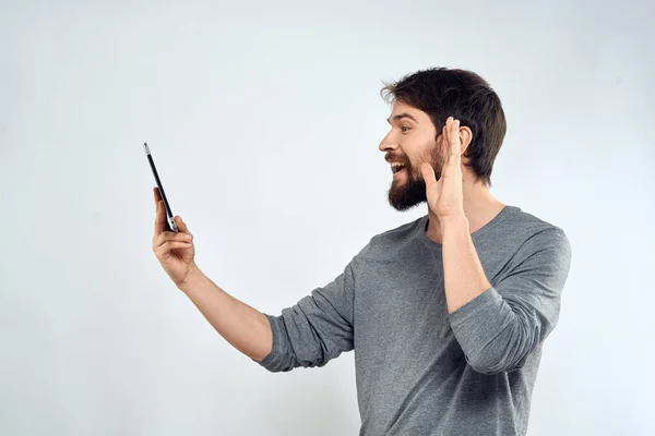 Een man met een tablet in zijn hand internet technologie communicatie grijze jas lichte achtergrond — Stockfoto