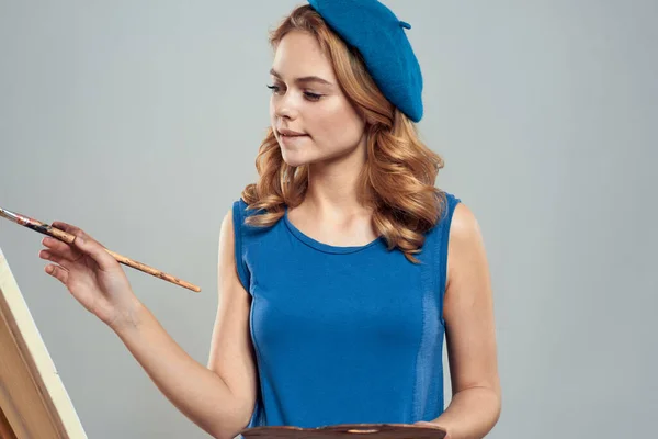 Donna artista blu basco tavolozza disegno su cavalletto arte creatività luce sfondo — Foto Stock