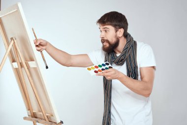 Ressam bir sehpada resim yapar. Bir fırça ve resim hobi olarak yaratıcılığın hafif arka planında bulunur.