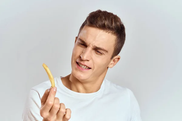 Emocional hombre celebración patatas fritas calorías comida rápida luz fondo blanco camiseta recortada ver — Foto de Stock
