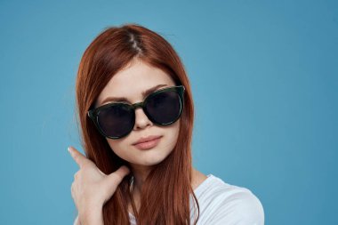 Güneş gözlüklü, uzun saç rujlu, yakın plan mavi arka plan.