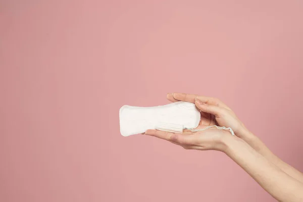 Almofada protetora e tampão em mãos femininas em um fundo rosa menstruação dias críticos — Fotografia de Stock