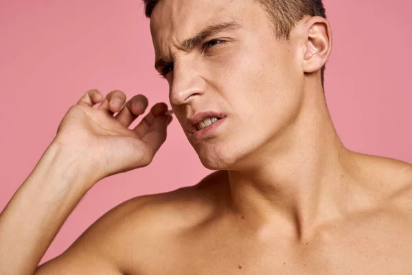 Emocionální muž s ušní holí v rukou na růžovém pozadí emoce oříznuté pohled na nahý trup — Stock fotografie