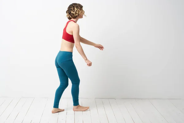 Mujer en leggings se dedica a la gimnasia en una sala de luz figura delgada deporte fitness —  Fotos de Stock