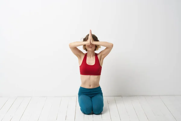 Kobieta w niebieskich dżinsach ćwiczy jogę na jasnym tle w domu i szczupłą figurę w gimnastyce — Zdjęcie stockowe