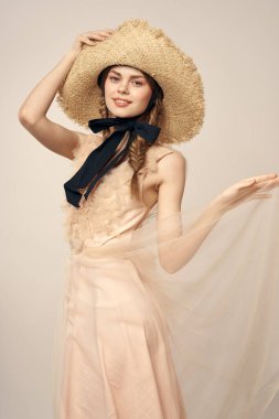 Bej elbiseli, hasır şapkalı, siyah kurdele takmış, manken görünümlü romantik bir kız.